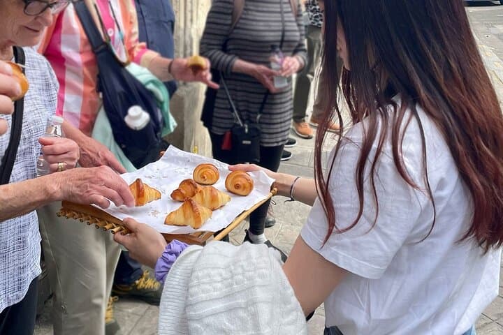 Croissant tray presented by young woman and older person picking a mini croissant
