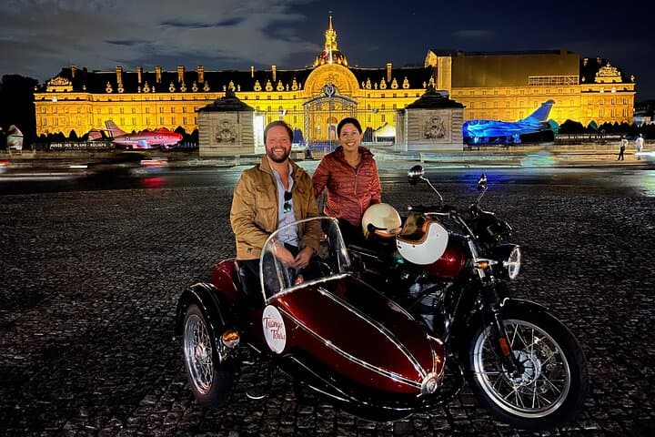 A couple enjoys a sidecar ride at night