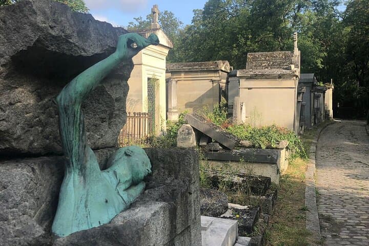 The tomb of the Belgian poet, George Rodenbach with the sculpture on his tomb shows him bursting out of the top of his crypt holding a rose in his outstretched hand at Père Lachaise Cemetery