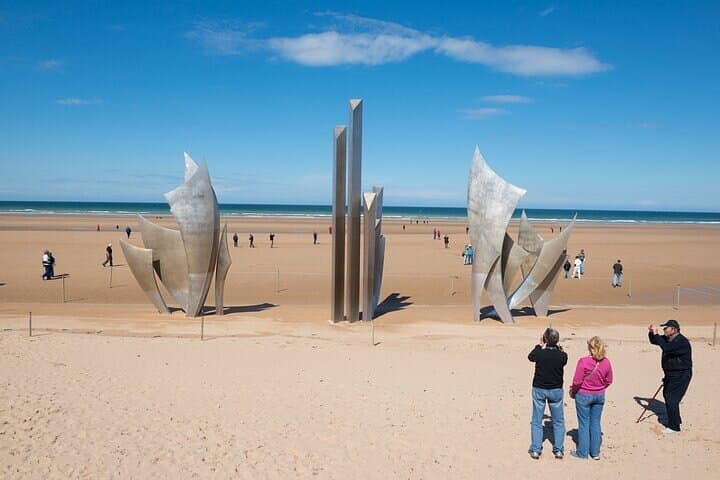 Tourists take photographs on Omaha Beach beside the sculpture entitled "The Braves" (Les Braves), created by Anilore Banon for the 60th anniversary.