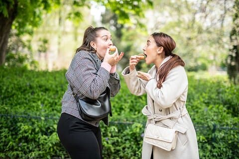 Two friends enjoying chou pastry during a food tour in Le Marais