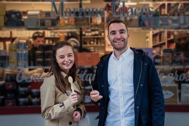 Happy couple with spoons in front of food shop