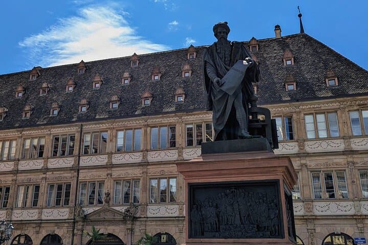 The shadow DE Johannes Gutenberg, father DE the printing press, looms in the centre DE the square. EN backdrop, the Chambre DE Commerce, this proud Renaissance building, named Neue Bau.