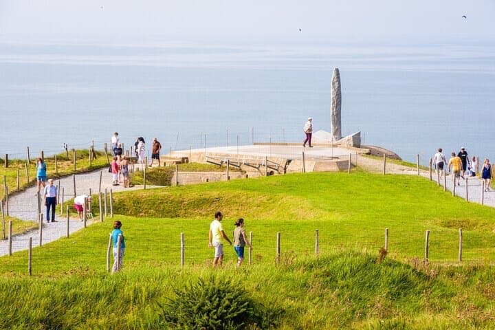 Tourists wander on the Pointe du Hoc path between bomb craters to the Ranger Monument erected in honor of the sacrifice of American troops on D Day.